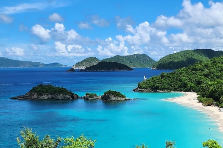 a small island in the middle of a body of water with Virgin Islands National Park in the background