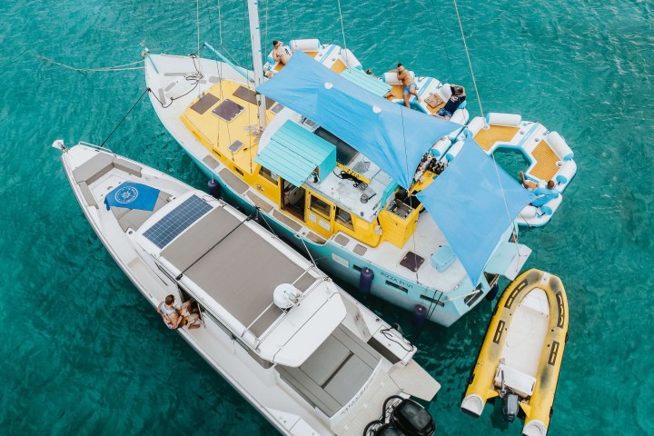 Aerial view of boats moored together in clear blue water.