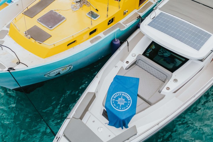 Two boats, one yellow and one white, docked together on turquoise water.